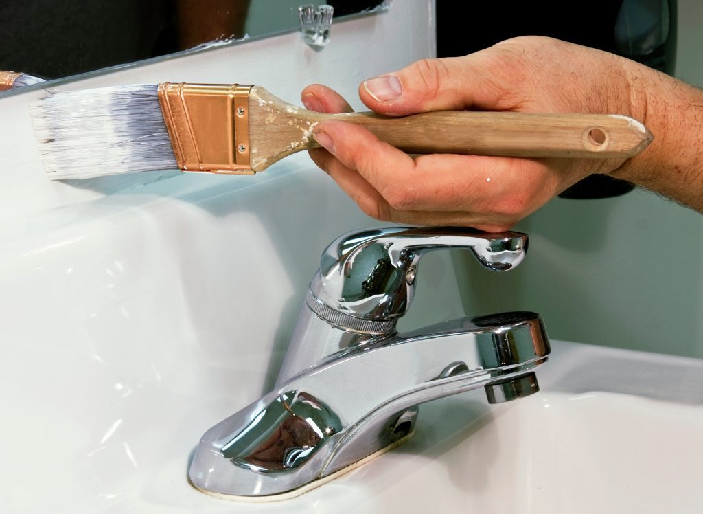worker painting a bathroom wall with white paint